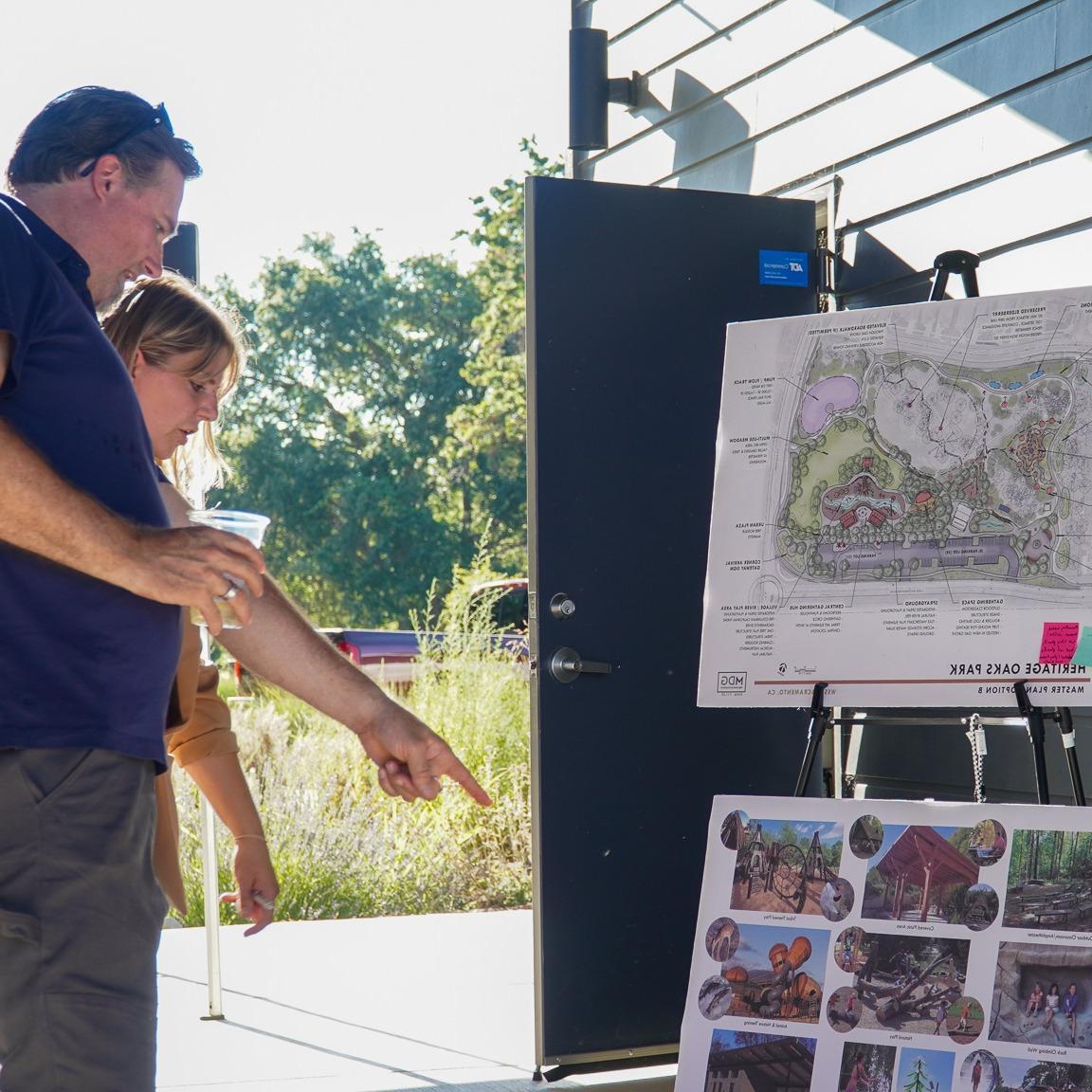 Man and woman pointing at Heritage Oaks Park Project board